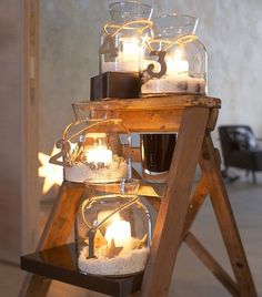 a wooden stand with candles in glass jars on top of it and lights inside the jar