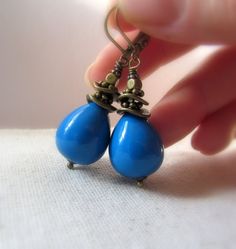 Chubby vintage teardrops in Denim Blue are wrapped by hand in decorative antiqued brass beads and suspended to dangle from matching antiqued brass lever back style ear wires. These lovely vintage beads are opaque and smooth with a shiny. Focal: Vintage opaque Denim Blue teardrops, 3/4'' tall Metal: Antiqued Brass Length: Approximately 2'' tall from the top of the ear wire, lightweight. Made with lead-safe and nickel free brass. These earrings are made to order. Please allow 2-3 business days bef Blue Teardrop Brass Earrings, Blue Bohemian Pearl Drop Earrings, Blue Pearl Drop Bohemian Earrings, Earrings Summer, Brass Beads, Summer Earrings, Vintage Beads, Summer Earring, Earrings Blue