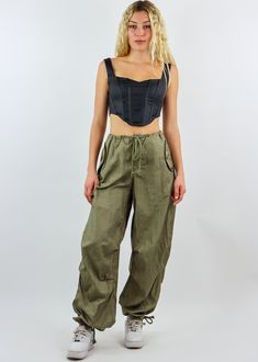 We are obsessed with these must have parachute pants! They feature an adjustable waist and ankle detailing with an oversized fit throughout the body. They are the most comfortable and trendy bottoms in fashion right now, and we can't wait to see you rock them! Wear them with your favorite crop top or oversized hoodie. Model Info Meet Zoe! Here she is wearing a size small. Hips: 35” | Waist: 25” | Bust: 32” | Height: 5’7” The Details Parachute Pants Adjustable Waist Adjustable Ankle Hand Wash Col Summer Combat Cotton Bottoms, Khaki High-waisted Cargo Parachute Pants, Khaki High Waist Cargo Parachute Pants, Spring Military Cargo Pants For Streetwear, Spring Military Style Cargo Pants For Streetwear, Military Style High Waist Parachute Pants In Khaki, Military Style High Waist Khaki Parachute Pants, Military Style Baggy Wide Leg Parachute Pants, Summer Streetwear Relaxed Fit Parachute Pants