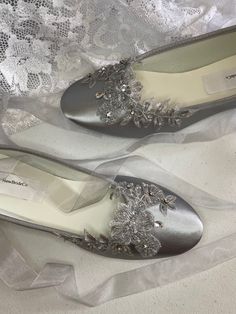 two pairs of silver shoes with flowers on them