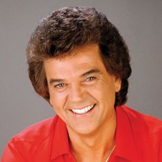 a smiling man in a red shirt is looking at the camera