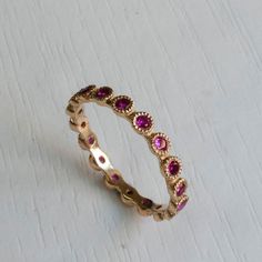 Gold Eternity ring set with Beautiful Pink Rubies. Famous for its passionate Pink-Red Color this July birthstone gemstone in one of finest and most sought after gemstones. Elegantly Set in a crown settings, Each ruby is 2mm in diameter with excellent color and clarity. This graceful Eternity ring has a dainty poise about it, getting lots of the right attention every time you wear it on its own or stack it with your other rings! Featuring between 15-22 Gemstones(Depending on ring size). Other sto Pink Gold Ruby Ring With Prong Setting, Pink Gold Round Ruby Ring With Prong Setting, Pink Ruby Round Jewelry, Pink Lab-created Ruby Ring, Pink Round Ruby Jewelry, Pink Ruby Ring Fine Jewelry Birthstone, Pink Sapphire Jewelry With Halo Design, Valentine's Day Pink Ruby Ring, Pink Ruby Promise Ring With Halo Setting