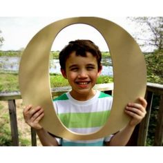 a young boy holding up an odd shaped object in front of his face and smiling