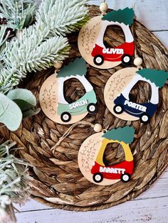 four wooden ornaments with cars on them sitting in a basket next to some pine branches