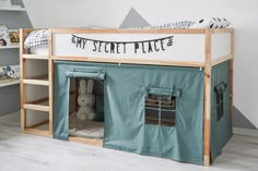 a child's loft bed with a tent on the bottom and a stuffed animal inside