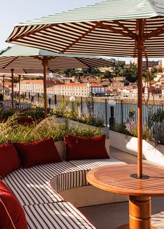 an outdoor seating area with striped umbrellas and potted plants on the roof terrace