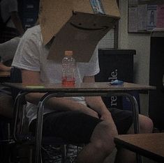 a person with a box on their head sitting at a desk in front of other people