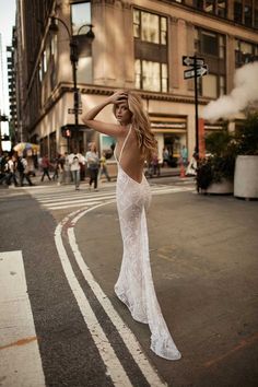 a woman in a white dress is standing on the street