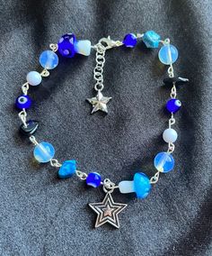 Blue beaded silver charm bracelet with stars, beads, beaded rocks, and evil eyes. Blue Star Charm Bracelet, Blue Beaded Bracelets With Silver Beads For Festivals, Celestial Style Beaded Bracelets As Gift, Blue Bohemian Jewelry With Star Charm, Bohemian Blue Jewelry With Star Charm, Bohemian Blue Star Charm Jewelry, Blue Festival Bracelets With Silver Beads, Blue Bracelets With Silver Beads For Festival, Blue Star-shaped Jewelry With Colorful Beads