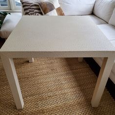 a white coffee table sitting on top of a carpeted floor next to a couch