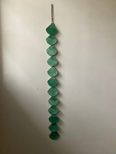 a long piece of green glass hanging on a wall next to a white wall in a room