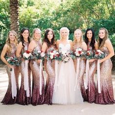 a group of women standing next to each other wearing dresses and holding bouquets in their hands