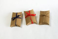 three wrapped gift boxes with red and blue ribbons tied in twine on white background