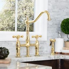 a kitchen sink with two faucets on the side and marble counter top in front