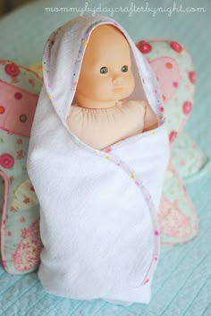 a baby doll wrapped in a blanket on top of a bed