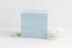 a blue box next to a candle and some baby's breath flowers on a white table