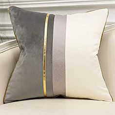 a gray and white pillow sitting on top of a couch