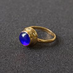 a gold ring with a blue stone in the middle on a black surface, close up