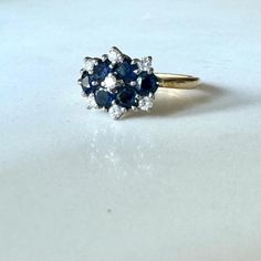 a blue and white diamond ring sitting on top of a table