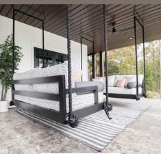 a porch swing that is attached to the side of a house with pillows on it