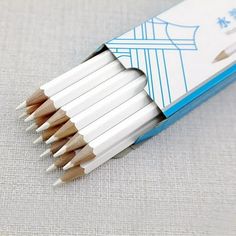 several white pencils are lined up in a blue and white box on a gray surface