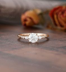 a diamond ring sitting on top of a wooden table next to rose buds and roses