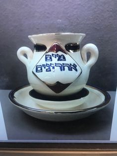 a white vase and saucer sitting on top of a glass plate in a display case