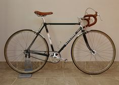 a black and white bike is on display in a room with tile flooring next to a wall