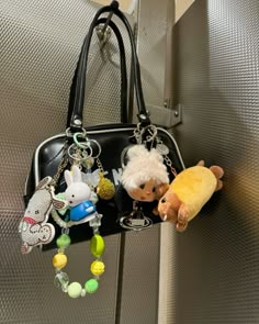 two small stuffed animals are hanging from a handbag on a hook in an elevator