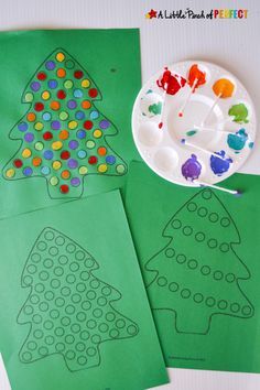 two paper plates with christmas trees on them next to some crafting material and paint