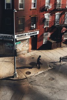 a man walking down the street in front of a building with a sign that says franklin cleaners