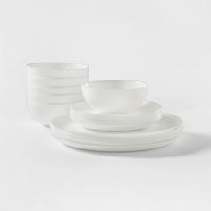 white dishes stacked on top of each other in front of a white background with one bowl and four plates