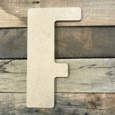 the letter f is made out of wood and sits on a wooden surface with planks