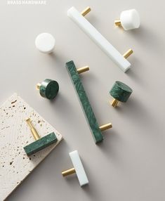 some white and green marble knobs and handles on a gray surface with gold accents