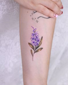 a small purple flower tattoo on the arm