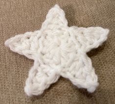 a white crocheted star on a brown surface with the end stitched together