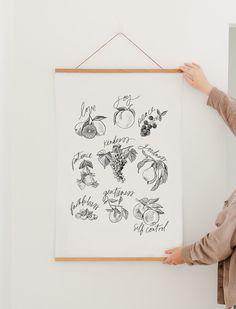 a woman is holding up a poster with fruits and vegetables on it in front of a white wall