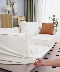 a person is pulling up the covers on a white couch