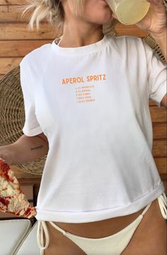 Introduce our trendy and comfortable Aperol Spritz T-Shirt! Show off your love for this delicious cocktail with this stylish shirt. Featuring a bold "Aperol Spritz" print on the front with a list of its classic ingredients. This crewneck is perfect for any casual occasion. Made from high-quality, soft and comfortable material, it's perfect for any weather. It's also a great gift for any loved one who is a fan of Aperol Spritz. Order yours today and raise a glass to good times in style! Perfect a Casual Screen Print T-shirt For Brunch, Summer T-shirt With Screen Print For Brunch, White Crew Neck T-shirt For Brunch, Trendy Crew Neck Tops For Brunch, Trendy Summer T-shirt For Brunch, White Short Sleeve T-shirt For Brunch, Short Sleeve Screen Print Tops For Brunch, Casual Screen Print Top For Brunch, Trendy White T-shirt For Brunch