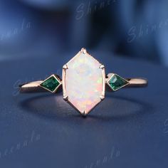 an opal and emerald ring on a table