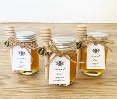 four jars filled with honey sitting on top of a wooden table