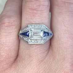 This Art Deco ring features a 1.15 carat emerald-cut diamond, I color and VS2 clarity, set in an east-west orientation. French-cut calibre natural sapphires are set on either side of the center diamond and continue along the shoulders. The center diamond and sapphires are surrounded by a halo of old European cut diamonds. This ring is vintage, and was handcrafted in platinum circa 1930.
The measurements of this ring are approximately 10.56mm x 19.18mm.
This ring can be resized to any finger size Art Deco Jewelry Vintage, Estate Diamond Jewelry, French Cut, Deco Ring, Art Deco Era, Deco Jewelry, European Cut Diamonds, Perfect Engagement Ring, Art Deco Ring