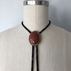 A lovely vintage bolo in perfect condition! Great gift for someone this holiday season! Introduction to Goldstone: Here's some good advice 🪶 Keep calm and carry the Goldstone crystal to ensure a golden future. Because let's be realistic--the mysterious abyss of the unknown--also known as the future--can be a daunting aspect. Known as the 'ambition' stone, the Goldstone crystal meaning is linked with boosting your drive and confidence, the essential mindset for paving the way for all your dreams 70s Jewelry Necklaces, Western Style Gold Lariat Jewelry, Brown Lariat Jewelry For Gifts, Adjustable Vintage Necklace For Collectors, Adjustable Retro Necklace For Gift, Vintage Brown Jewelry For Western-themed Events, Handmade Elegant Bolo Ties As A Gift, Handmade Elegant Bolo Ties For Gift, Western Lariat Jewelry For Festival