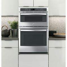 a stainless steel double oven built into the wall in a kitchen with white cabinets and counter tops