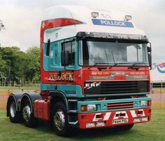 a red and blue truck parked on top of a lush green field