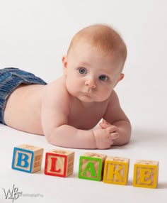 a baby laying on its back with blocks spelling out the word blare in front of it