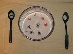 three black utensils sitting on top of a white table cloth next to a plate