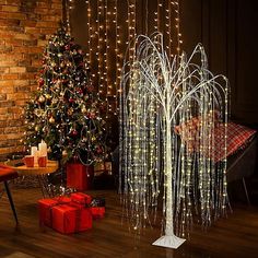 a christmas tree with lights in front of a brick wall and presents on the floor