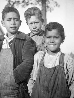 an old black and white photo of three boys standing next to each other with their arms around one another