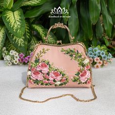 a pink purse sitting on top of a white table next to flowers and greenery